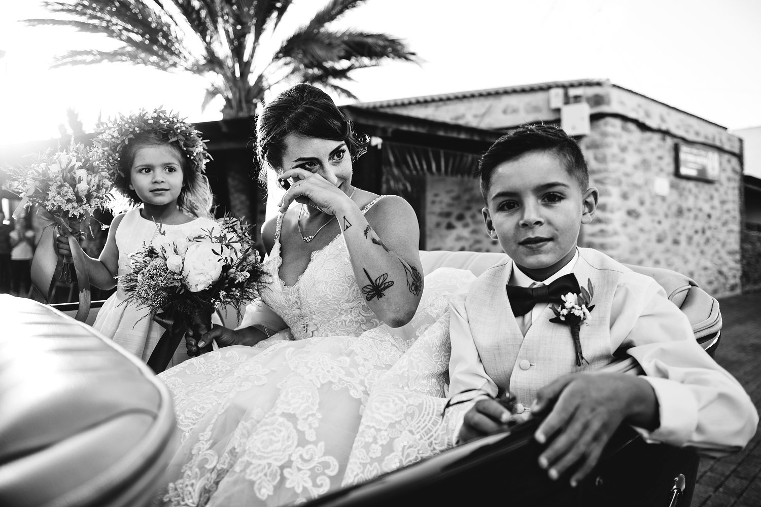 Novia secándose las lágrimas junto a dos niños durante una boda en Fuerteventura, en una fotografía en blanco y negro.