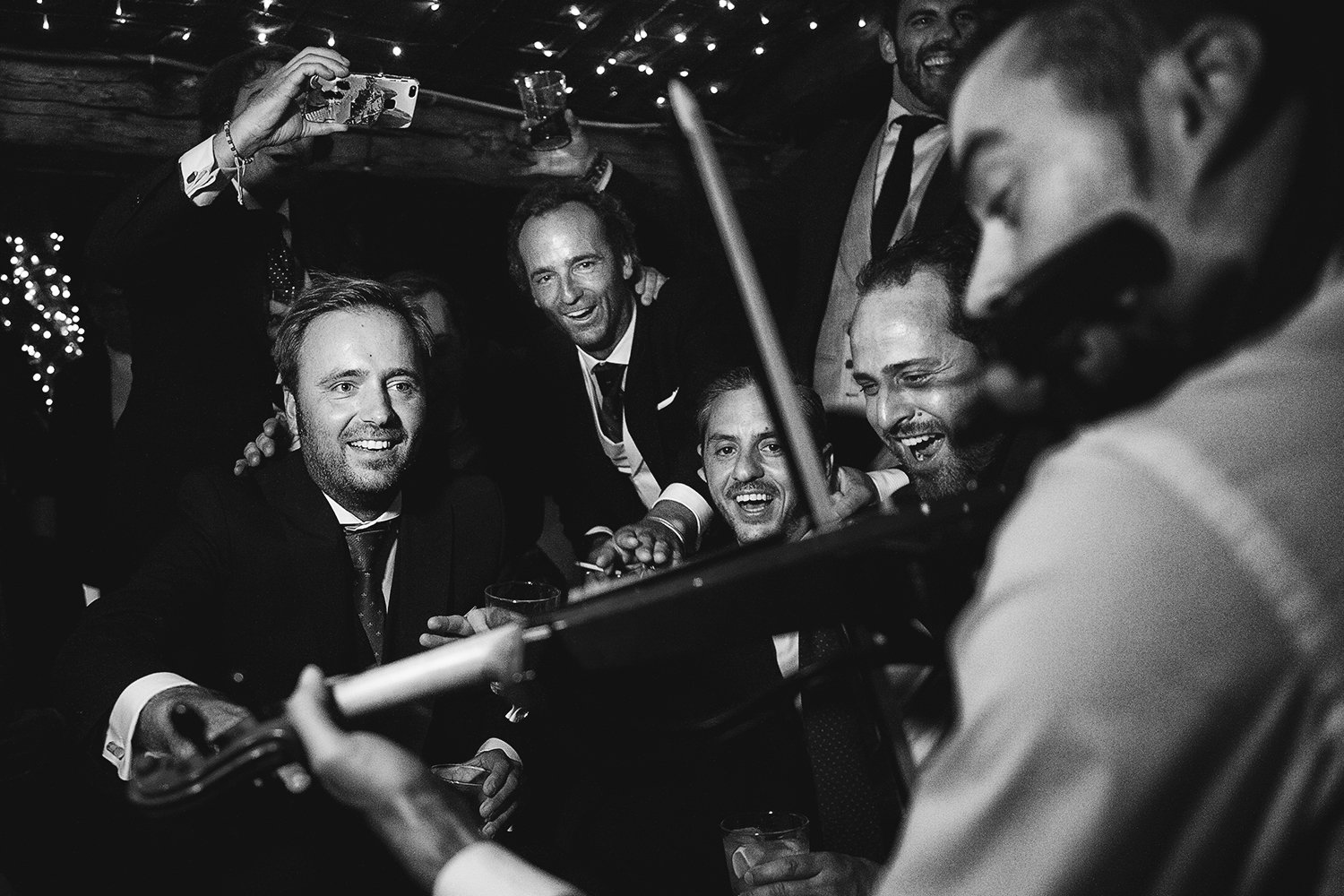 Amigos de Maud y Juan cantando alrededor de un músico durante la fiesta de su boda en Extremadura.